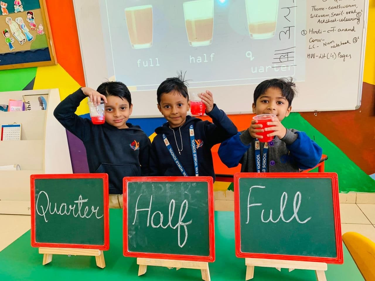 Three students holding cups next to chalkboards labelled quarter, half and full